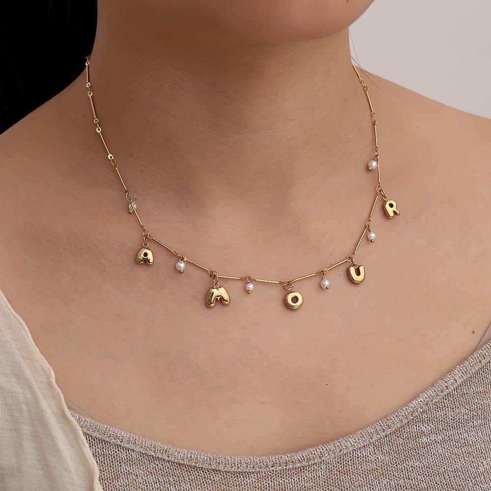 Goldene Edelstahlkette mit Amour-Schriftzug und kleiner Perle.